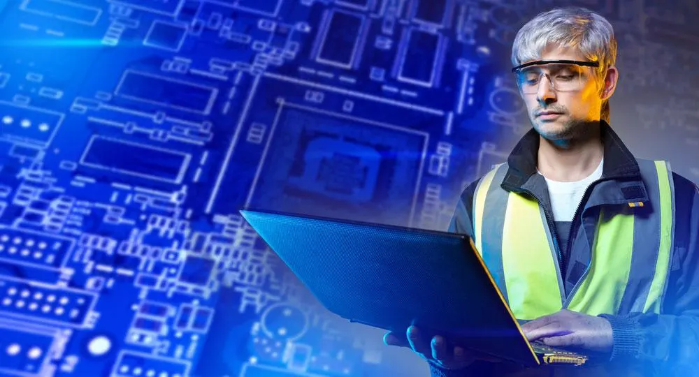 Inżynier elektronik projektujący koncepcję na laptopie z obrazem płytki drukowanej za nim
